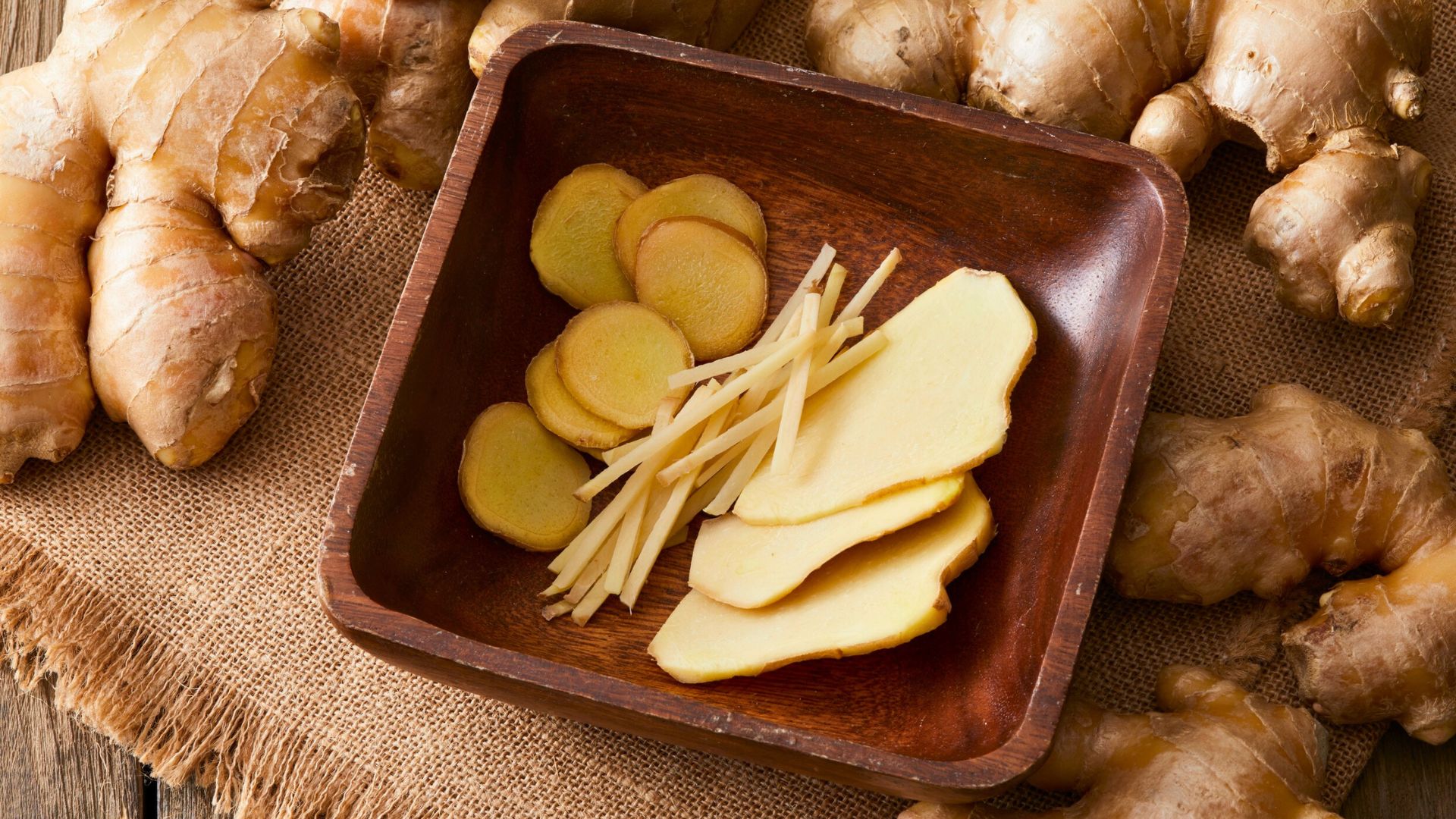 Fresh ginger root with sliced and julienned pieces on a wooden plate, representing ginger as a food considered for babies