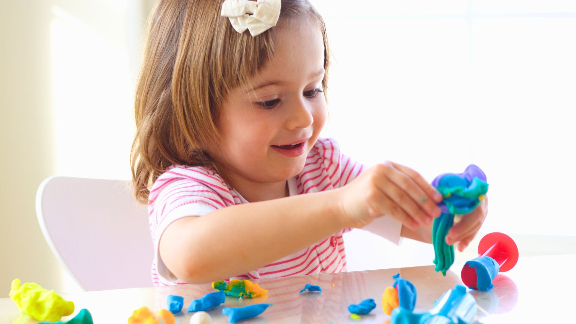 Playdough Activities for Toddlers Toddler sitting at a table playing with colorful playdough