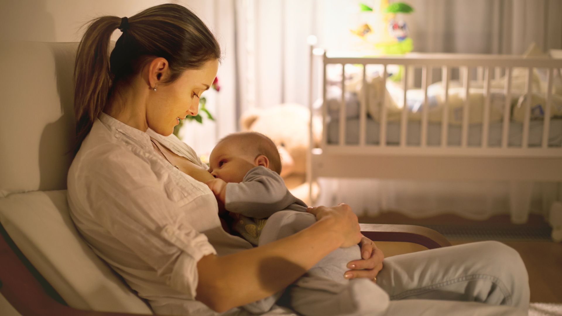 Mother breastfeeding her baby in a nursery while considering the pros and cons of breastfeeding