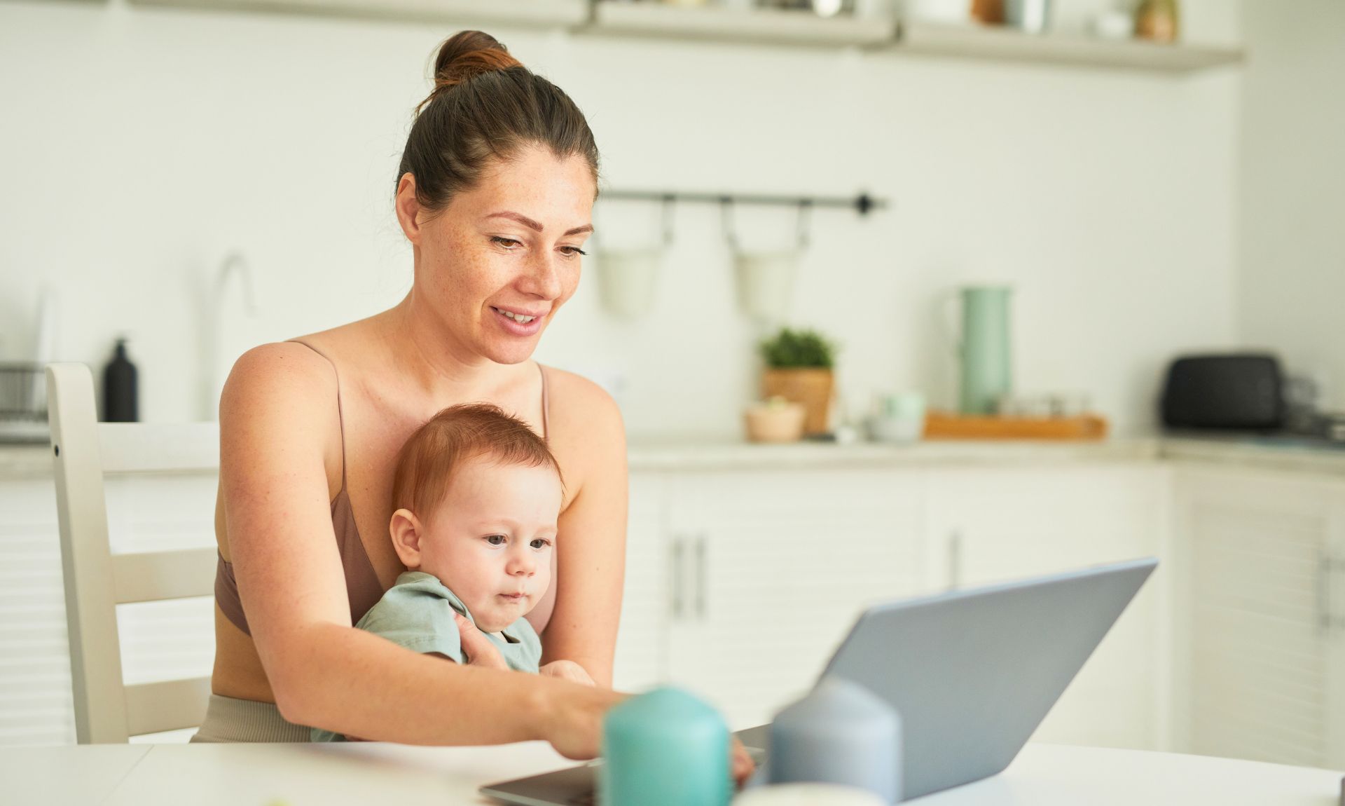 Raising Tot useful information A mother and child looking at parenting resources on a laptop in the kitchen.