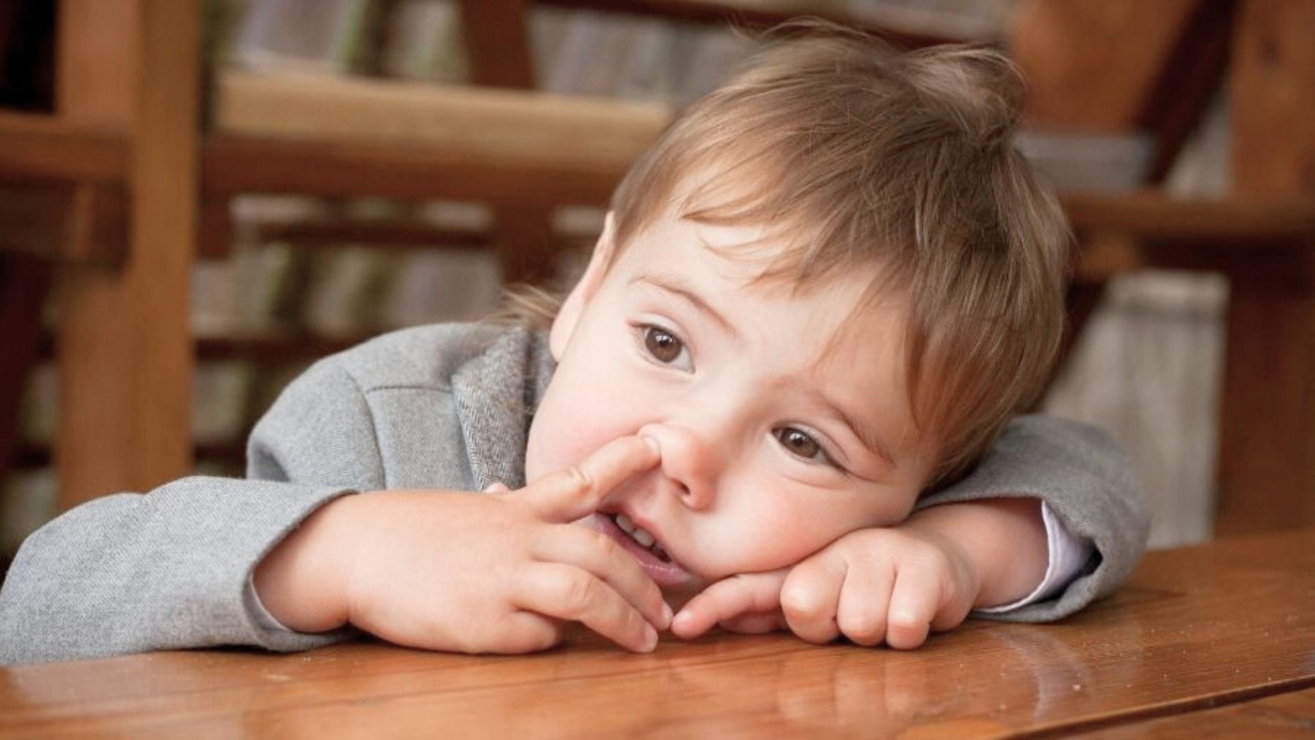 Baby resting on a table while picking their nose